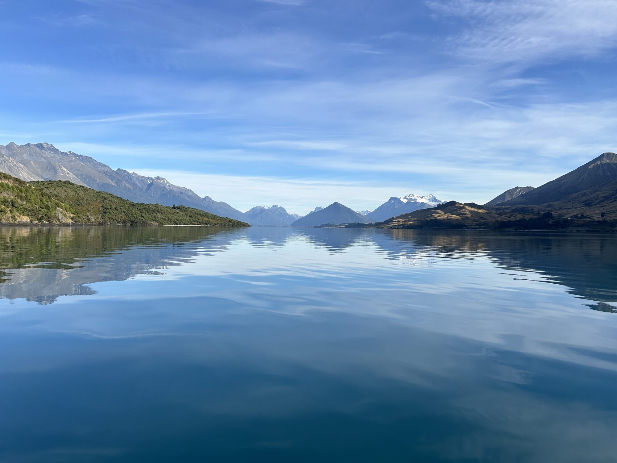 Lake Whakatipu, on the way to Pigeon Island, on a calm and sunny day, looking towards the mountains in the distance