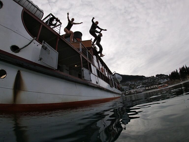 Swimmers jump from the top deck of the TSS Earnslaw boat into the waters of Lake Whakatipu