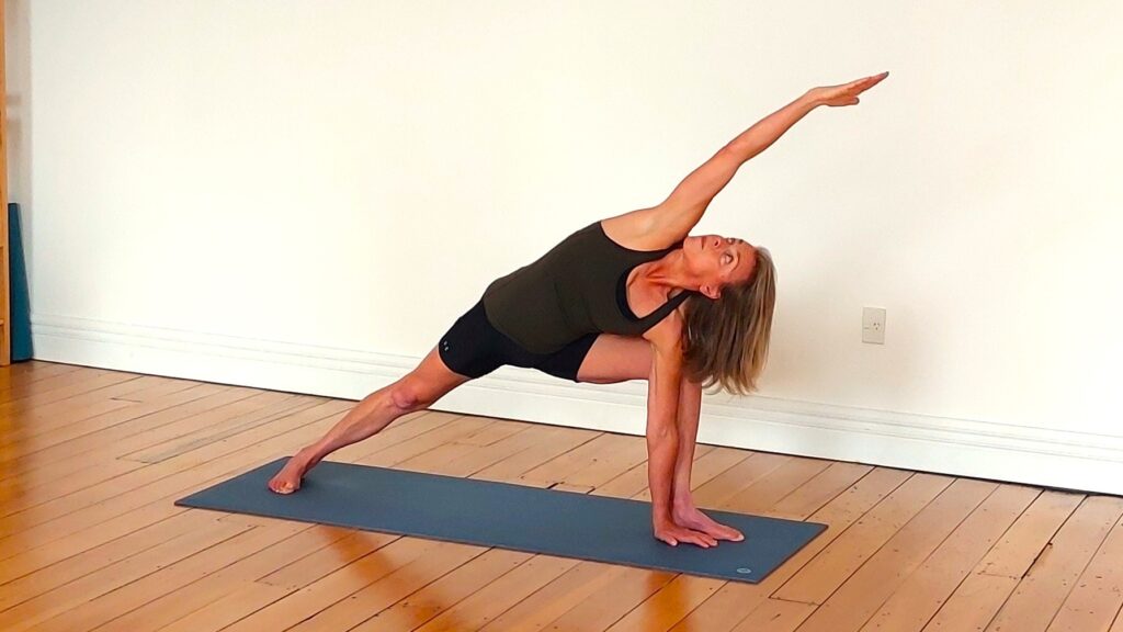 Woman in black tank top and shorts doing parsvakonasa yoga move for swimmers