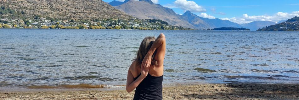 woman doing yoga for swimmers on Queenstown beach