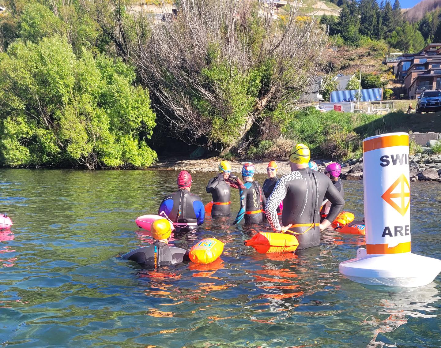 Swimmers in wetsuits and tow float prepare to swim in Queenstown